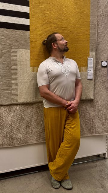 Sören an eine Wand gelehnt, nach oben blickend, in gelber Hose